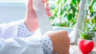 Doctor with ECG and foam heart on his desk
