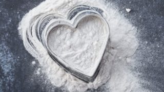 Arrowroot flour with heart shaped tray on a granite backdrop