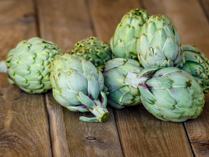 A closeup view of fresh artichokes on a wooden table
