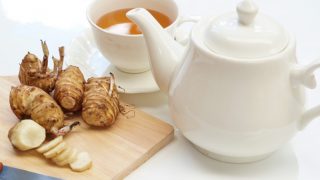 Artichokes kept next to a teapot and cup filled with artichoke tea