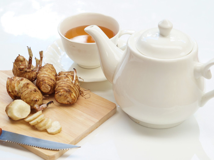 Artichokes kept next to a teapot and cup filled with artichoke tea