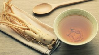 Close-up of ashwagandha root on a tray, cup of tea and wood spoon