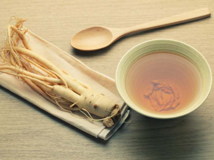 Close-up of ashwagandha root on a tray, cup of tea and wood spoon