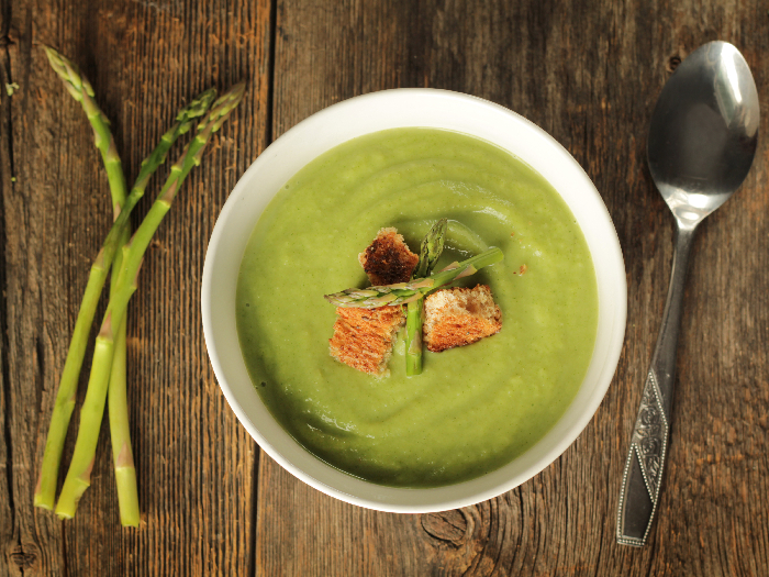 Top view of a asparagus soup in a white bowl on a rustic background