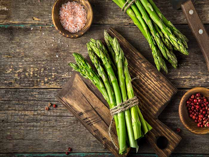 Asparagus stalks tied in bundles on a wooden counter