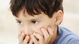 Close-up of a small boy suffering from autism on a white background