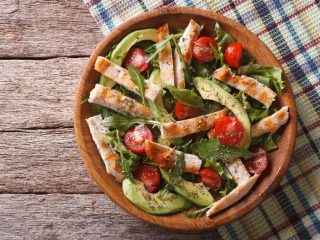 avocadochickensaladone Chicken salad with avocado, arugula and cherry tomatoes in a wooden plate.