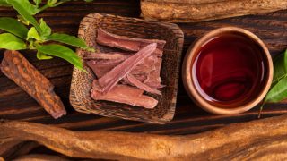 Ayahuasca in a wooden bowl along with a cup of tea