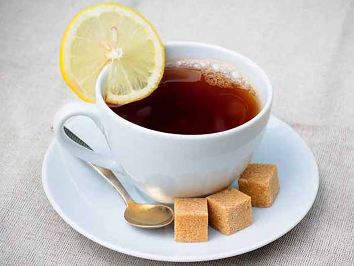 A cup of ayahuasca tea and brown sugar cubes with a spoon in a saucer