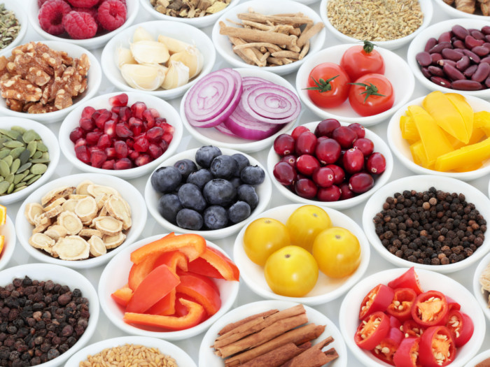 Fresh spices, fruits, vegetables, and beans in white bowls
