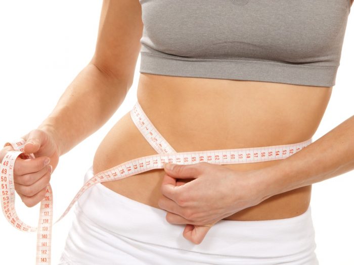 Close-up of a woman in gym clothes with a tape measure around her waist