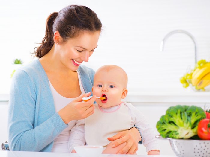 A happy mother feeding food to her baby
