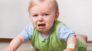A crying baby lying on her tummy.