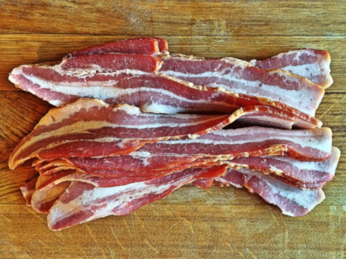 Raw bacon slices on a wooden table
