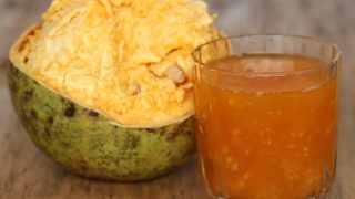 Bael fruit next to a glass of bael fruit juice