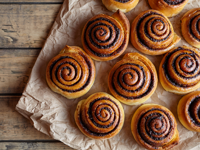 Freshly baked cinnamon buns with spices and cocoa filling on parchment paper