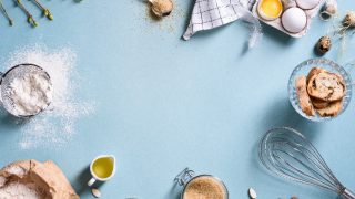 Baking ingredients such as eggs, whisk, almonds, a jar of melted butter, a sack of flour