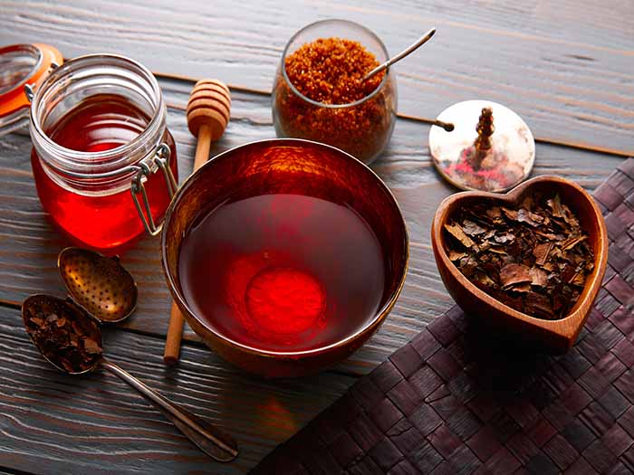 Bancha tea kept atop a table, next to dried bancha tea leaves, honey, and brown sugar