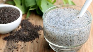 Basil seed drink with a white bowl of dried basil seeds on a wooden table