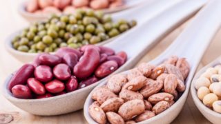 Close up of spoons with varieties of lentils and beans on a wooden table