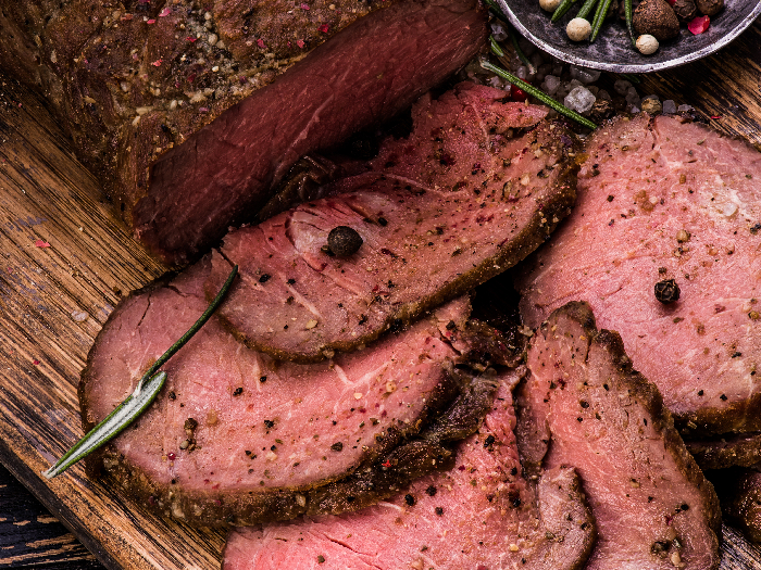 Roast beef tenderloin on a cutting board with salt and pepper