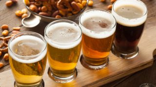 Different types of beer with a bowl of snack on a wooden table