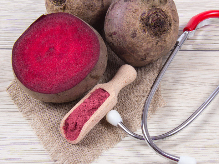 Whole and sliced beetroots, a scoop of beetroot powder, and a stethoscope