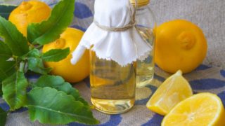 2 small bottles of bergamot essential oil with bergamot fruits on a table mat