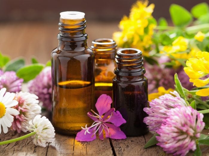 Three essential oil bottles surrounded with colorful flowers