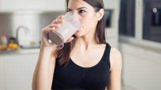 Woman in gym clothes drinking a shake.