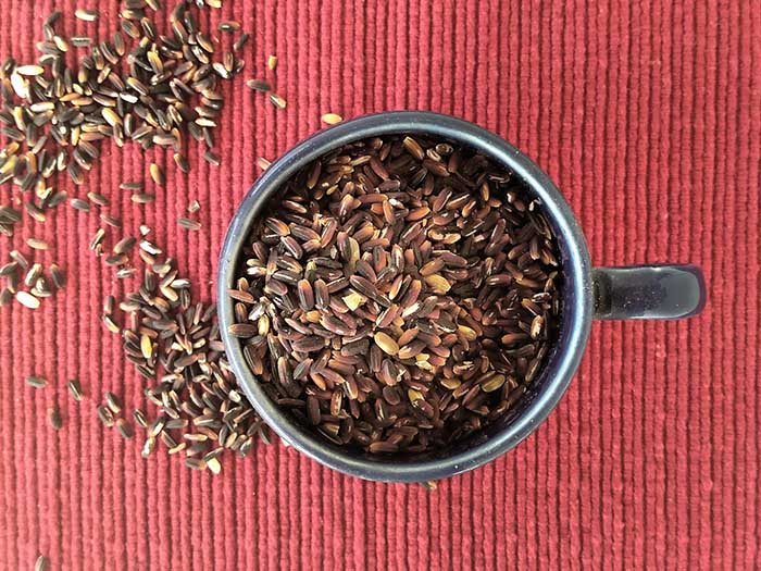 A bowl of black rice on a red placemat