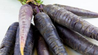 A bunch of black carrots on a white background