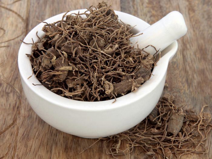 Dried black cohosh in a mortar & pestle on a wooden surface.