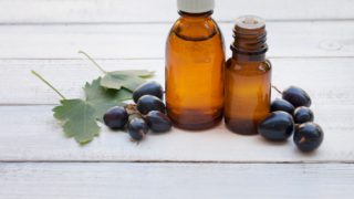 Black currant oil in essential oil bottles with fresh black currants and leaves