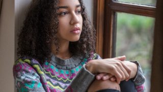A female teenager looking sad/depressed/thoughtful looking out of a window