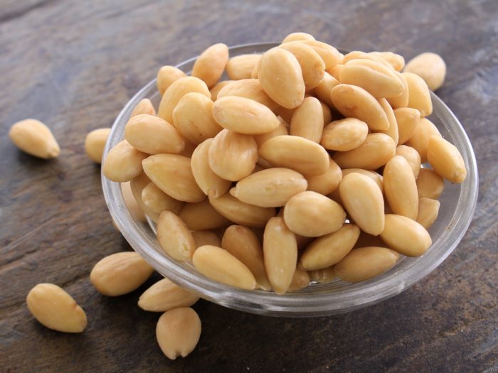 Blanched almonds in a bowl against a wooden background
