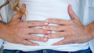 A woman clenching her stomach with both hands
