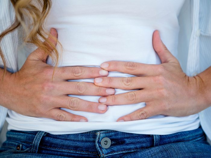 A woman clenching her stomach with both hands