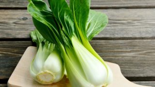 Close-up image of two bok choy florets on a wooden cutting board