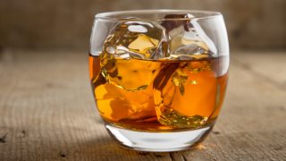 Brandy with ice in a glass placed on a wooden table