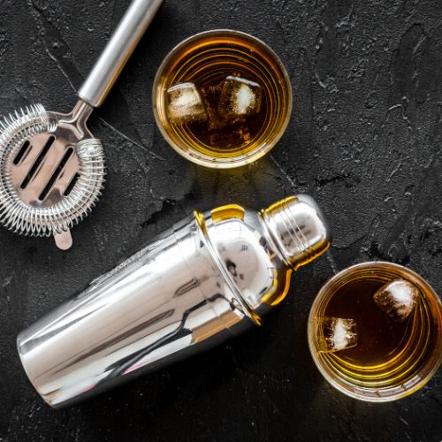 Top view of brandy cocktails with bartender tools on a slate background