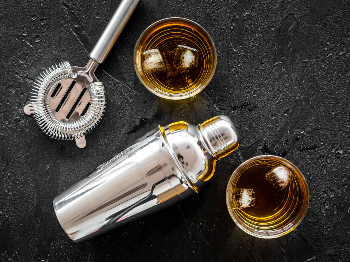 Top view of brandy cocktails with bartender tools on a slate background