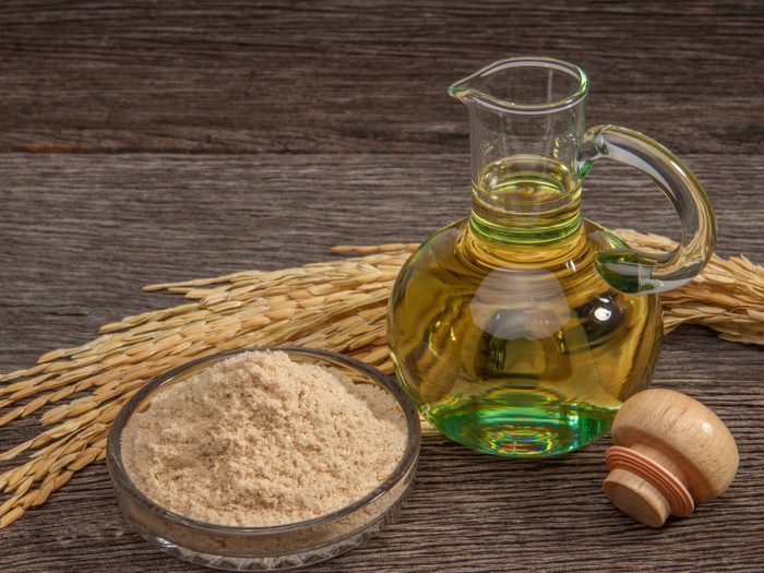 A jar of bran oil with unmilled rice bran on a wooden table