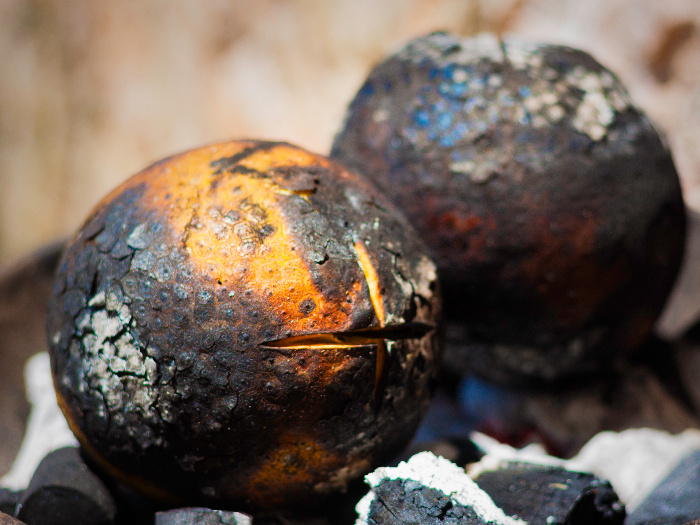 Whole breadfruit being roasted on charcoals