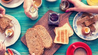 Top view of a breakfast spread with toast, jam, eggs, coffee, poridge, fruits and juice