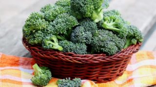A basket of raw broccoli florets on a wooden table