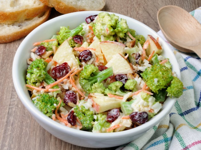 broccoli cranberry salad with sliced apples in a white bowl