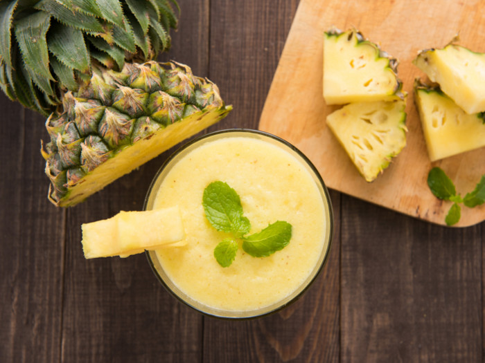 Flatline picture of cut pineapples and a glass of juice topped with mint leaves.