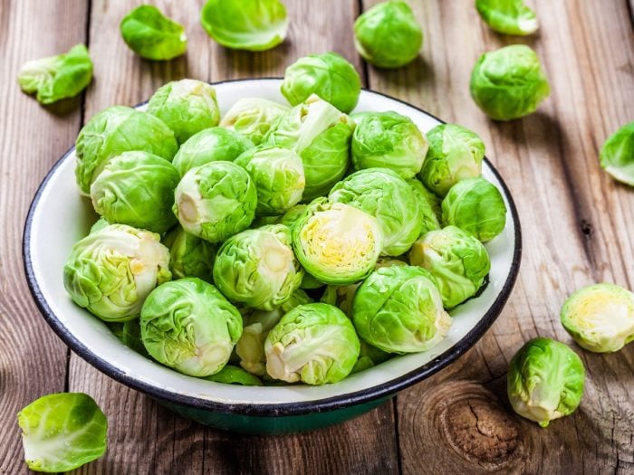 Fresh green Brussels sprouts in a ceramic bowl on a wooden table