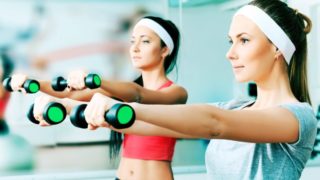Two women doing light weight lifting indoors